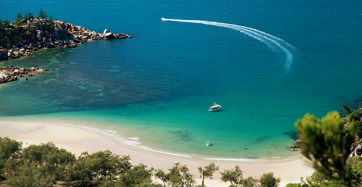 A tour boat moored over reef flats in the Great Barrier Reef's turquoise water.