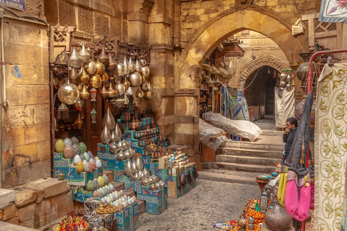 A brass lantern stall inside Khan el-Khalili bazaar, ornate lanterns hanging under a stone archway.