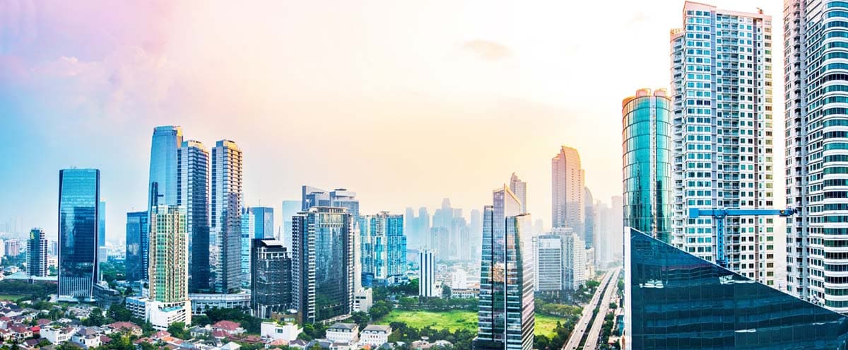Jakarta's high-rise skyline under a hazy tropical sky.