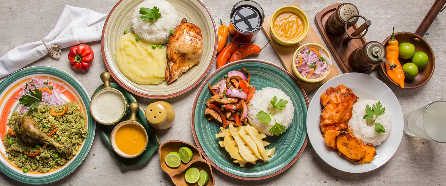 A spread of Peruvian dishes — ceviche, causa and roasted corn — on a restaurant table.