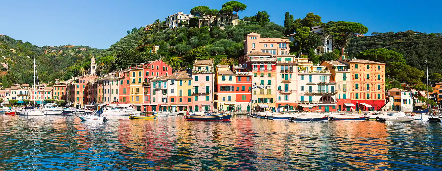 Portofino's pastel harborfront houses curving around a small boat-filled bay on the Italian Riviera.