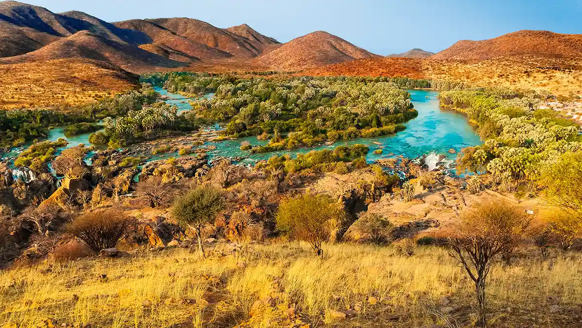 Die Epupa-Fälle am Kunene vom Aussichtspunkt — weiße Kaskaden zwischen Baobabs und Makalani-Palmen an der Grenze zu Angola.