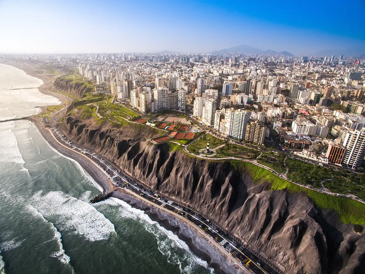 Le scogliere di Miraflores a Lima sopra il Pacifico al crepuscolo, con la strada costiera che curva in basso.