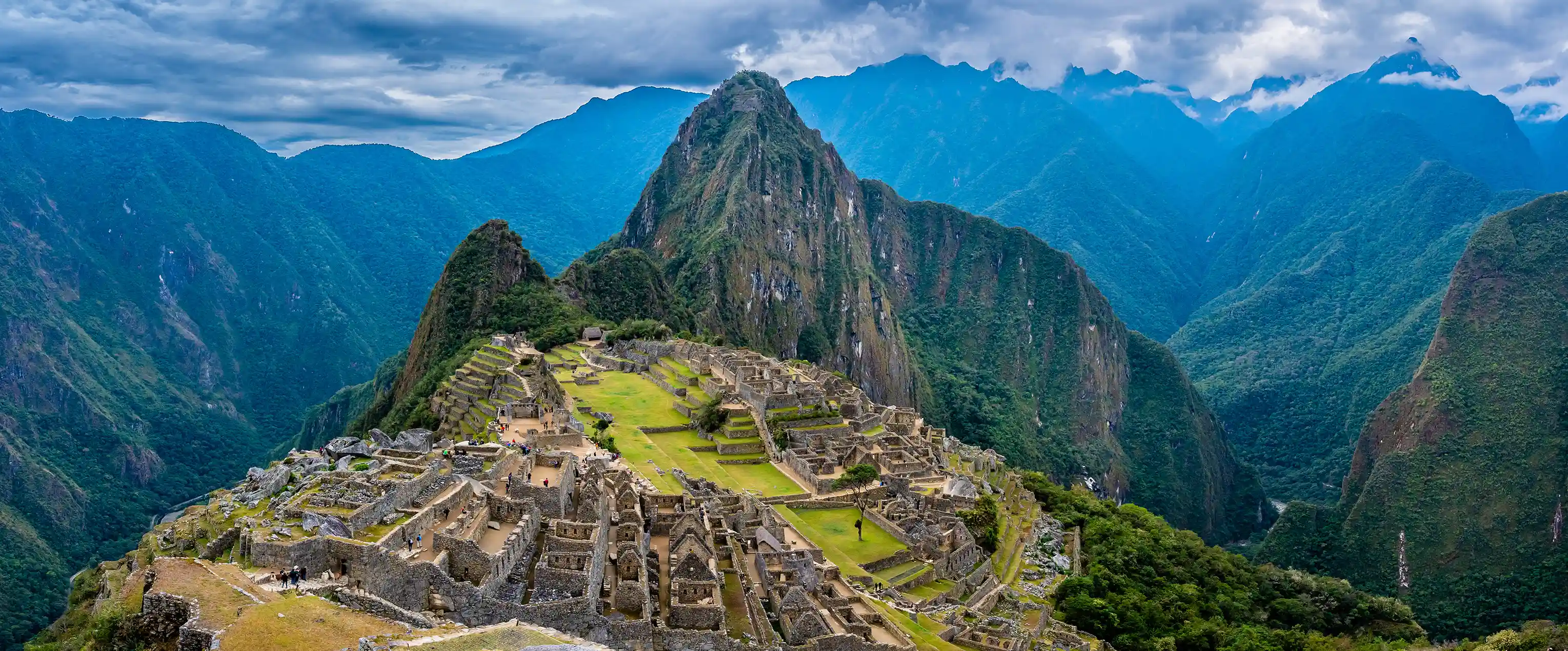 Machu Picchu's stone terraces and ruins with Huayna Picchu rising behind them.