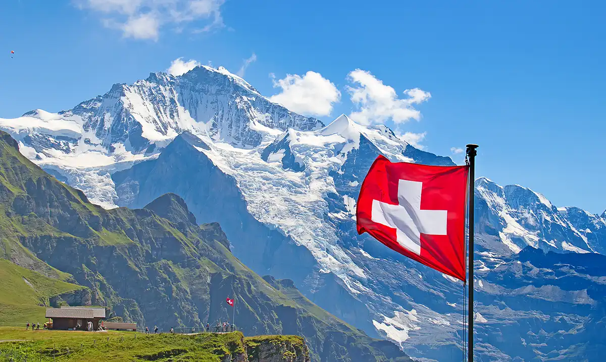 Snow-capped Swiss Alps above a green valley.